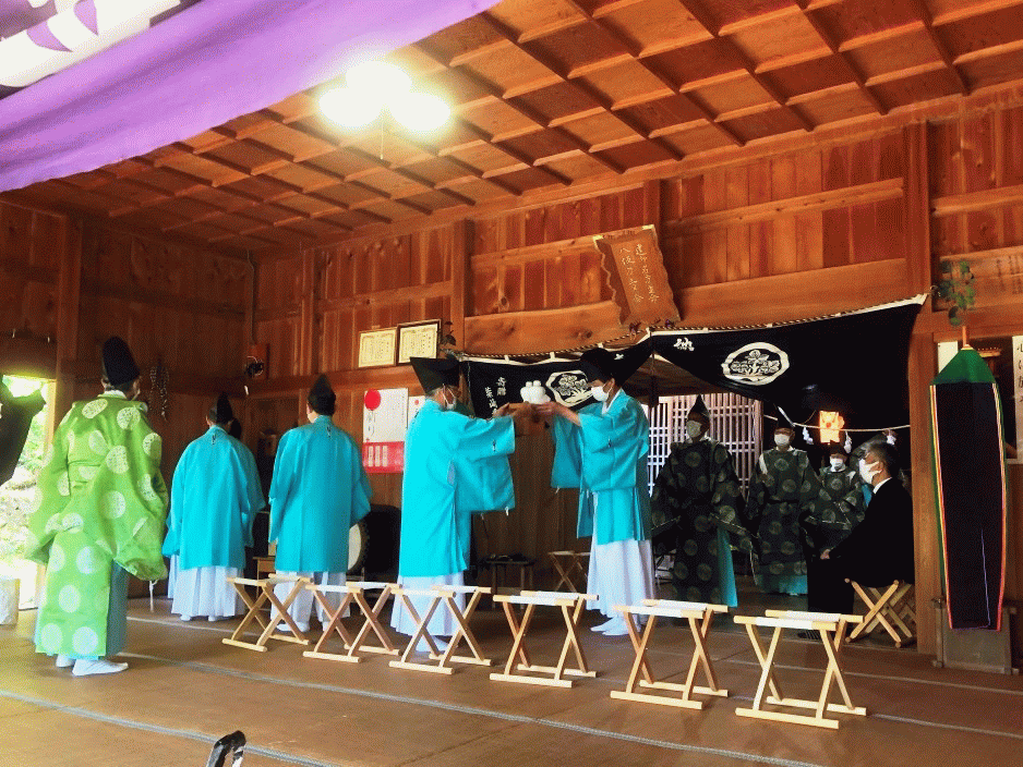 各組で神社の係(世話人)になると誰もが経験する供え物のリレーです。画面左端の緑装束が池場の伊藤さんで(禰宜(ねぎ)様です）、所作の指導をして下さっています。